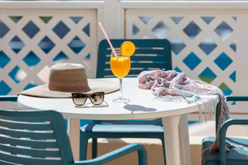Une table ronde avec des boissons et des accessoires de soleil sur une terrasse.