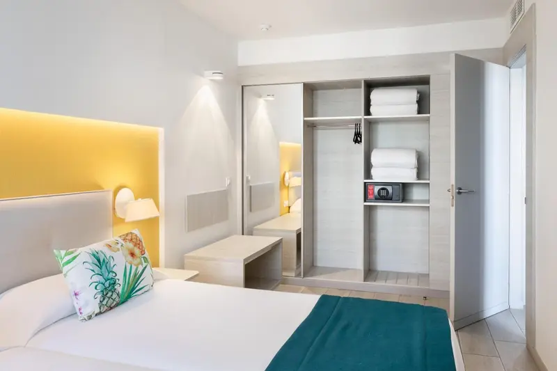 Une chambre lumineuse avec un grand lit et un placard intégré.
