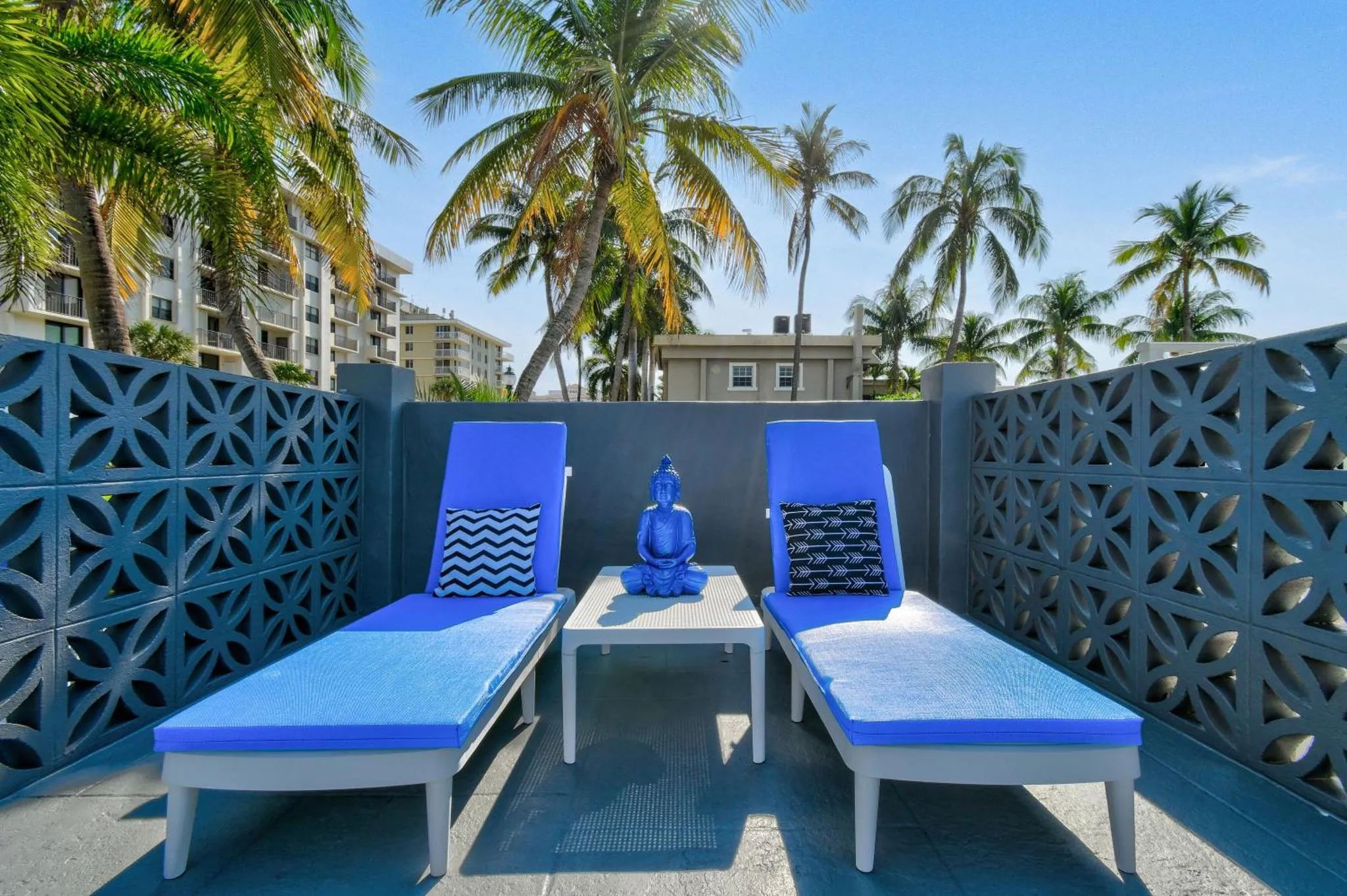 Deux transats bleus et une statue de Bouddha sur une terrasse ensoleillée.