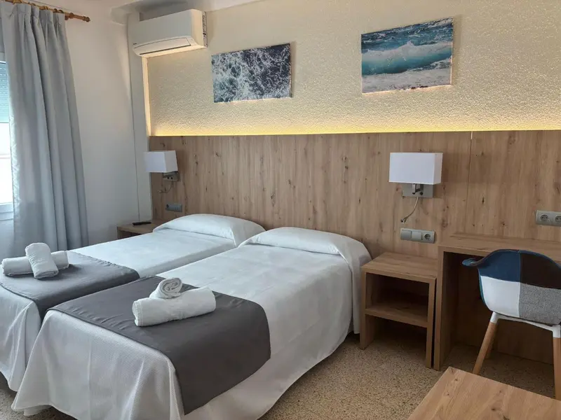 Chambre lumineuse avec deux lits simples et une décoration sobre.