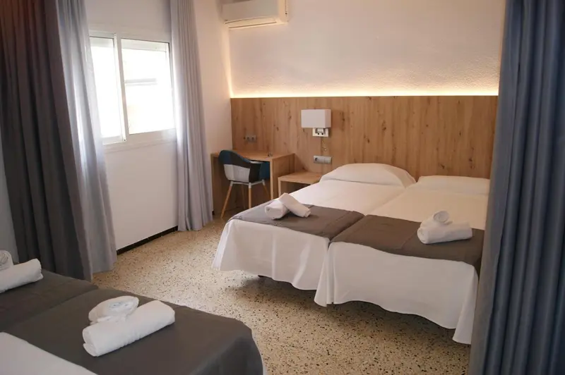 Une chambre lumineuse avec deux lits simples et un bureau.