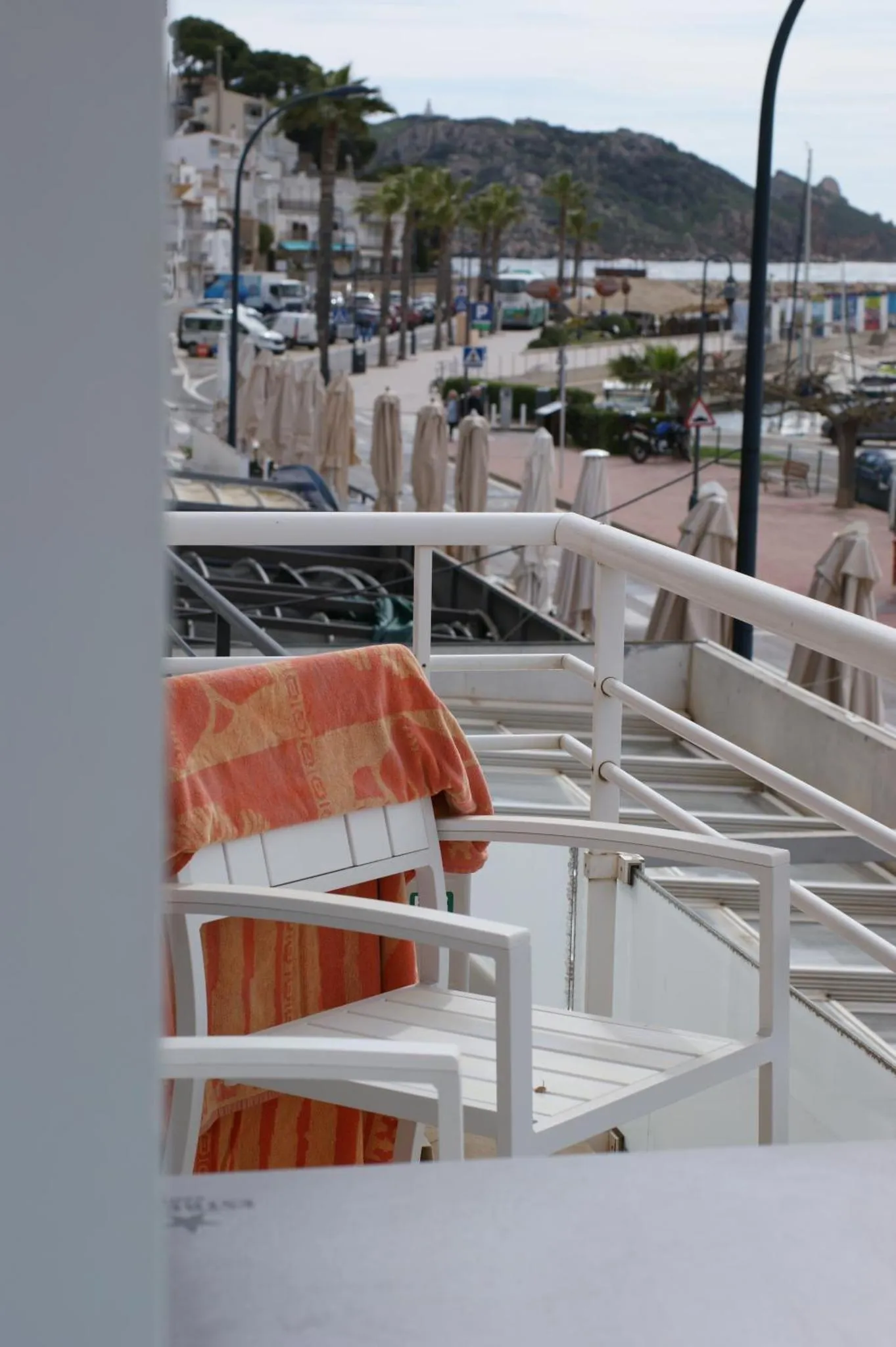 Terrasse avec mobilier blanc et vue sur une promenade en bord de mer.