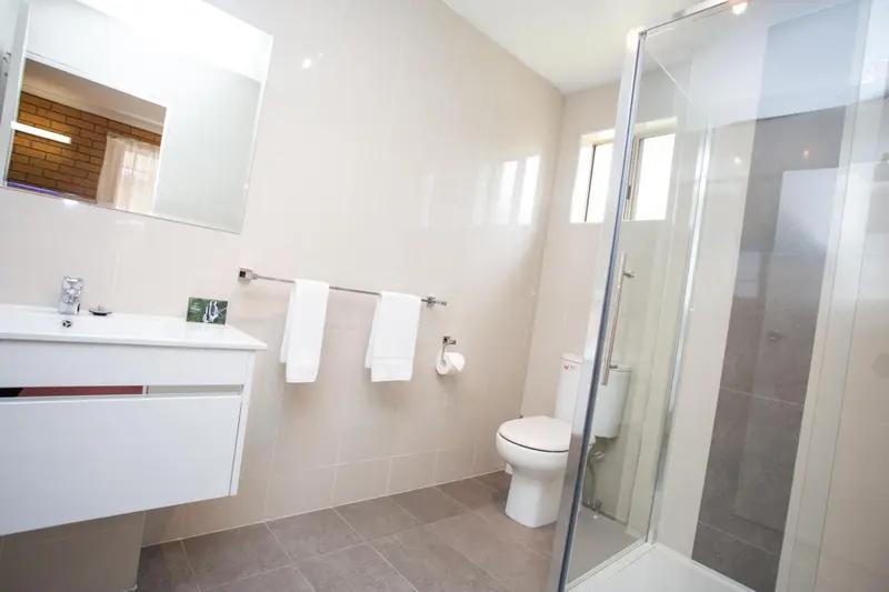 Une salle de bain claire avec douche à l'italienne et lavabo.