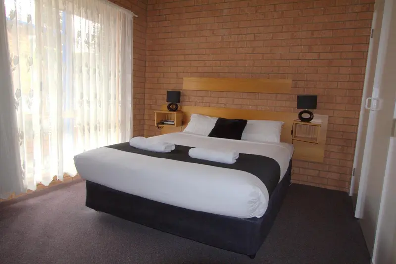 Une chambre avec un grand lit recouvert d'une couette blanche et noire.