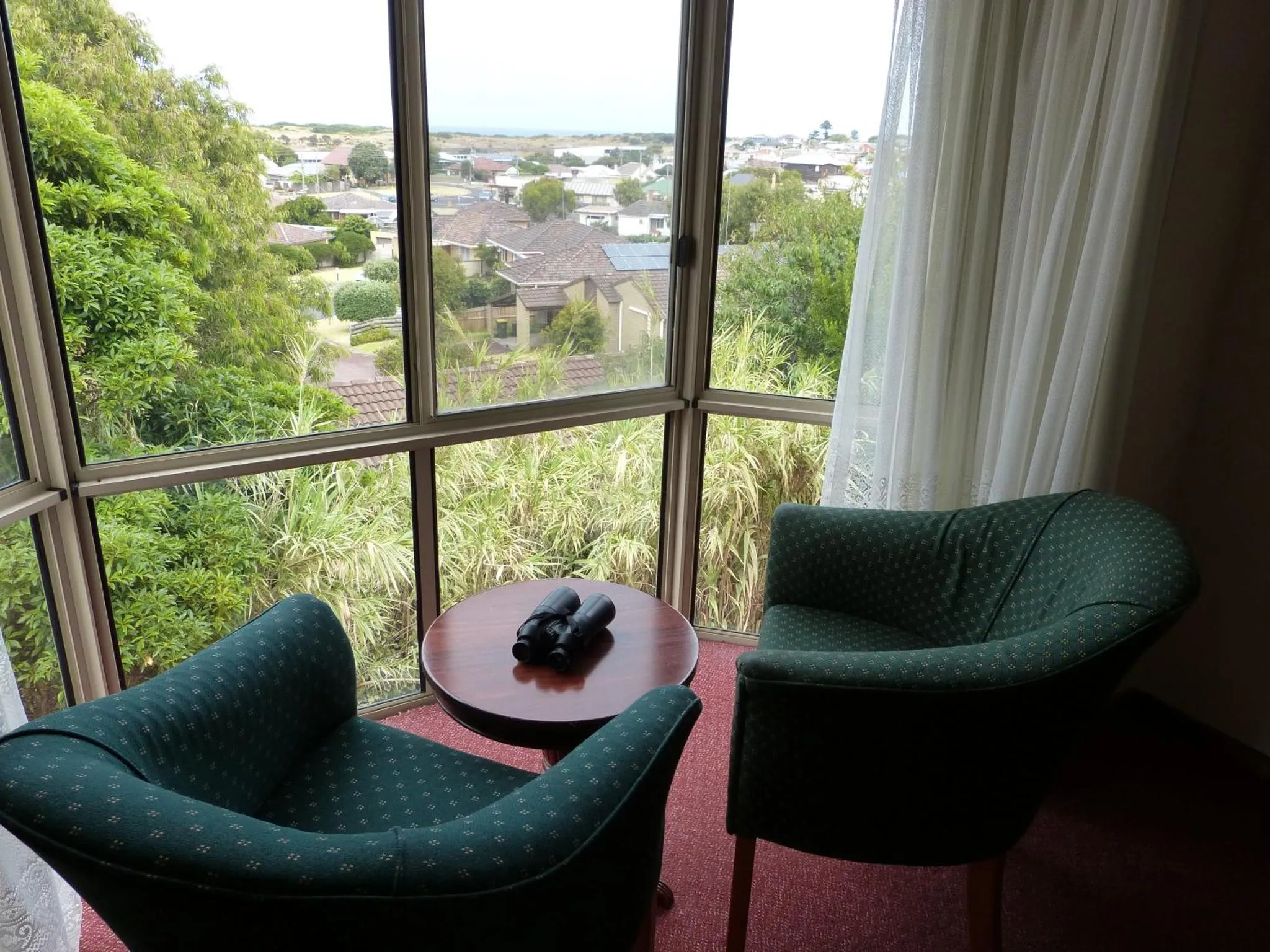 Espace de détente avec deux fauteuils et une table basse devant une grande fenêtre.