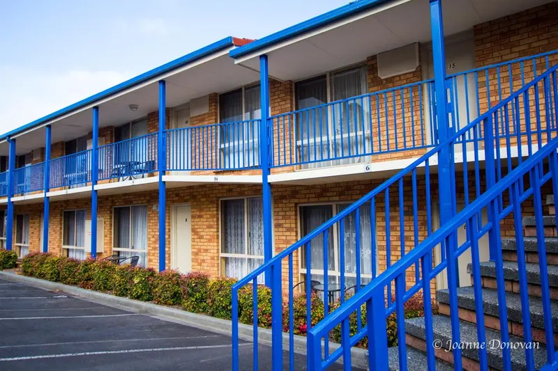 Façade d'un bâtiment avec des balcons et des escaliers bleus.