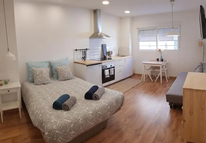 Un espace de vie lumineux avec un lit et une kitchenette.