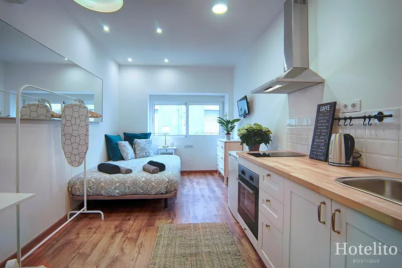 Une kitchenette lumineuse s'ouvre sur un espace de couchage avec un lit simple.