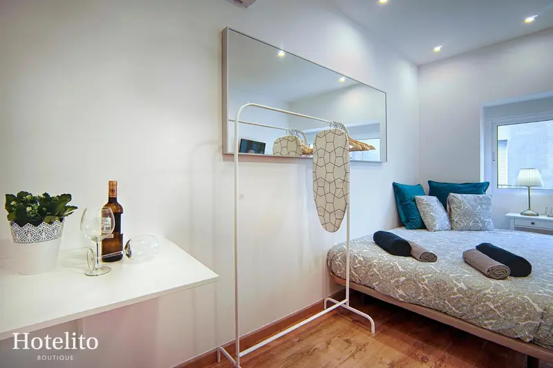 Une chambre lumineuse avec un lit et un portant à vêtements.