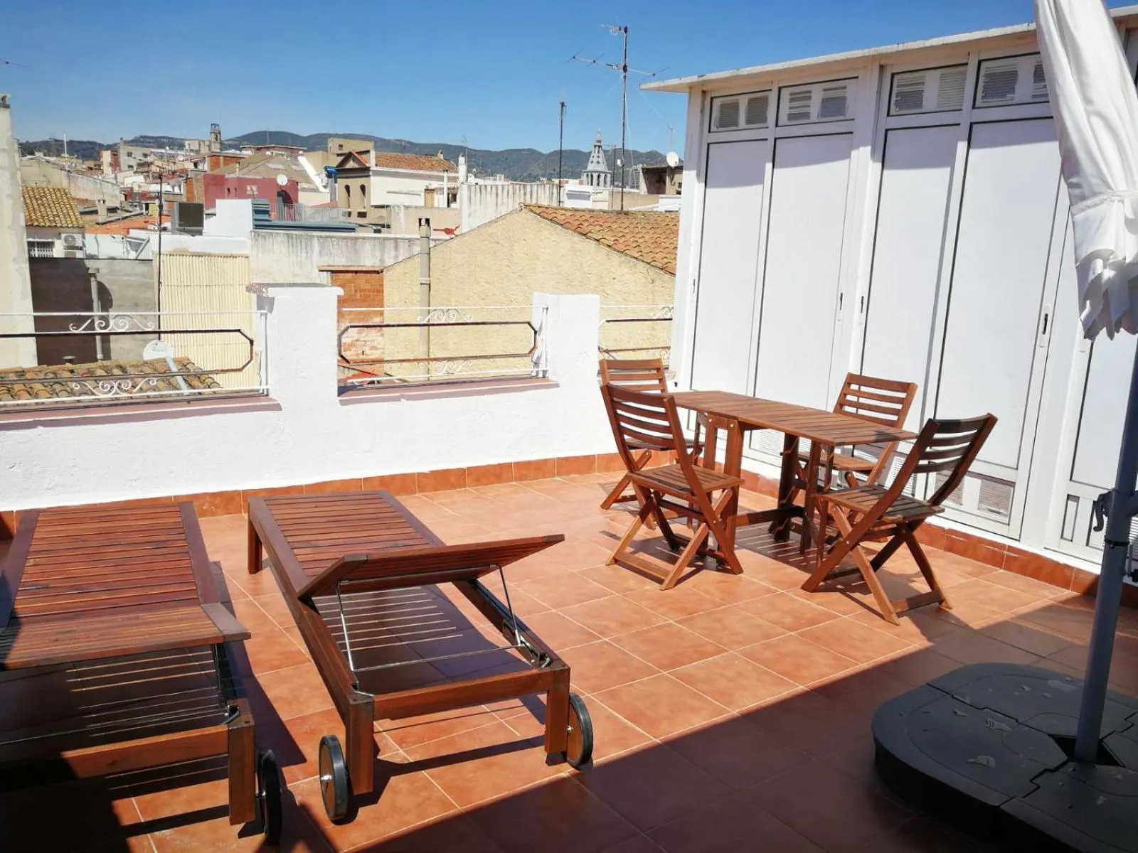 Terrasse aménagée avec mobilier de jardin et vue sur la ville.