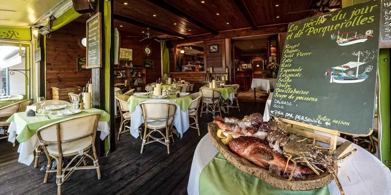 Une salle de restaurant lumineuse avec des tables dressées et un présentoir de poissons frais.