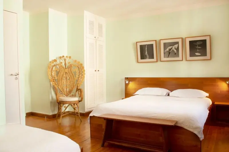 Une chambre lumineuse avec un grand lit et une chaise en bois sculpté.