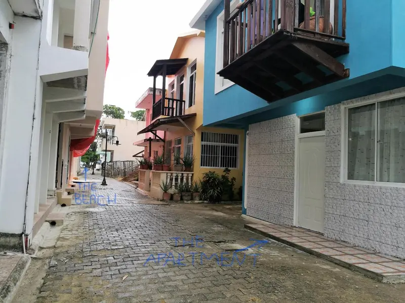 Allée pavée entre des bâtiments colorés avec des balcons et des fenêtres.
