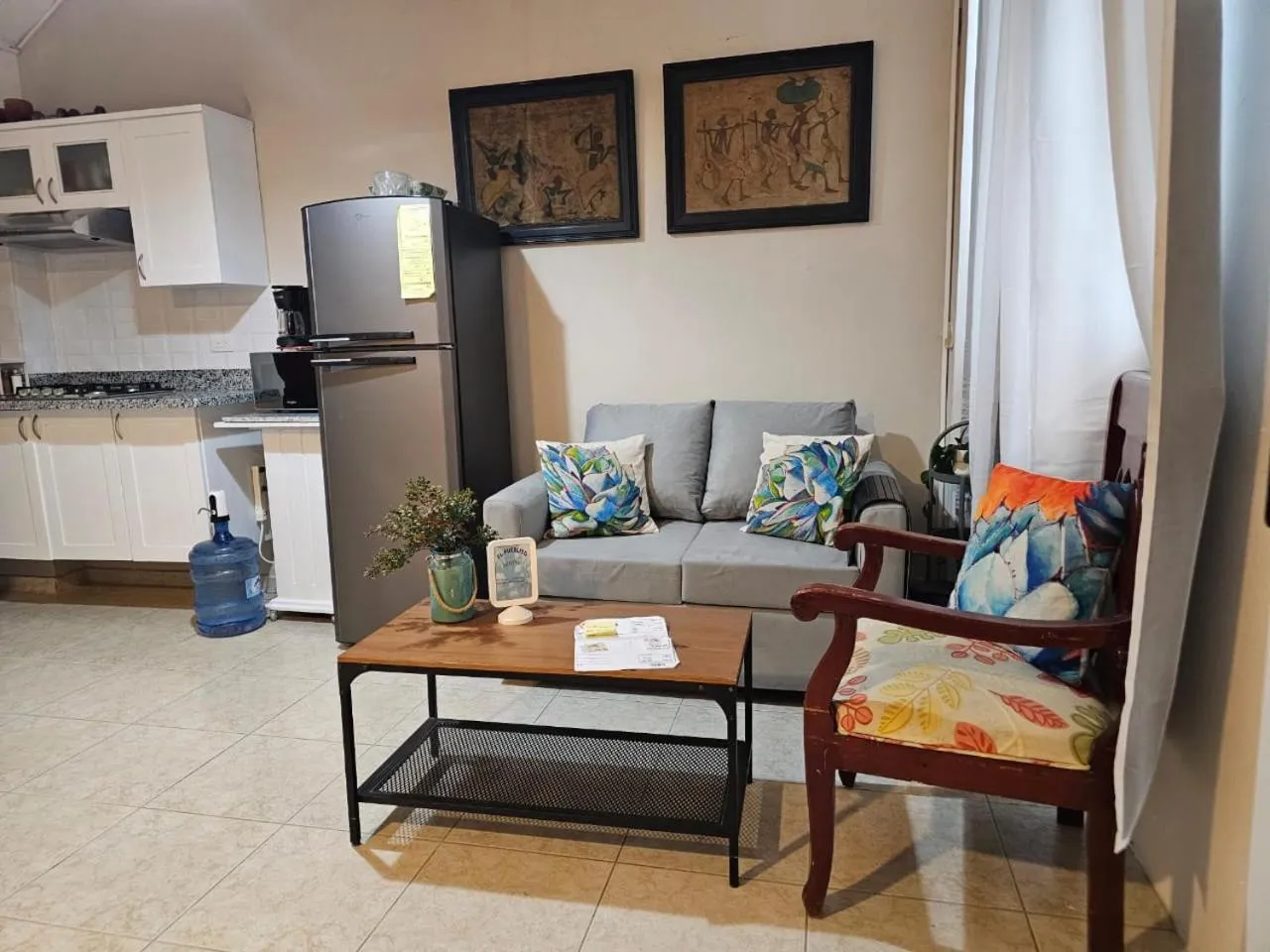 Interieur lumineux avec canape, table basse et cuisine ouverte.