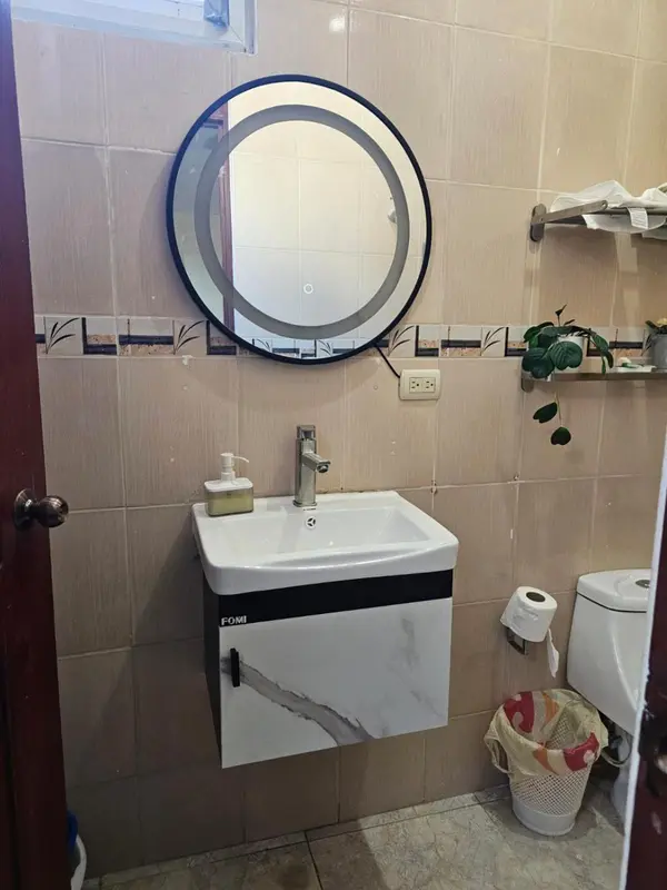 Une salle de bain avec lavabo, miroir et toilettes.