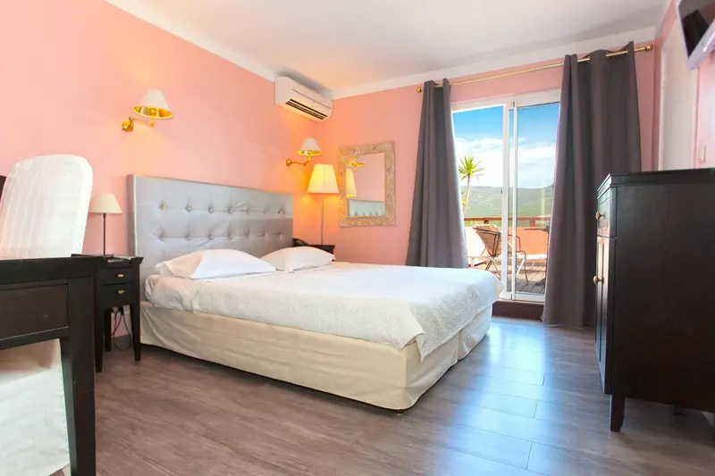 Une chambre lumineuse avec un grand lit et un accès à une terrasse.