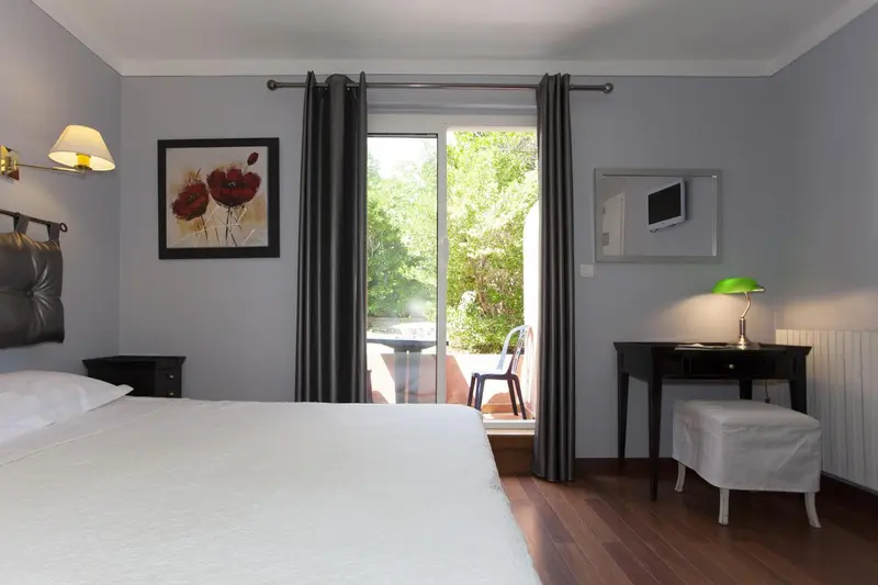 Une chambre lumineuse avec un lit blanc et un accès à une terrasse.
