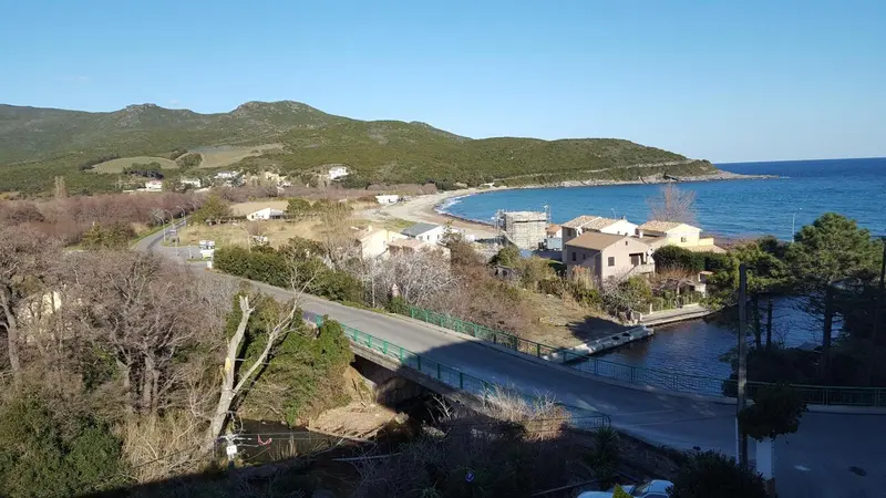 Vue aérienne d'un village côtier avec une route sinueuse et une plage.