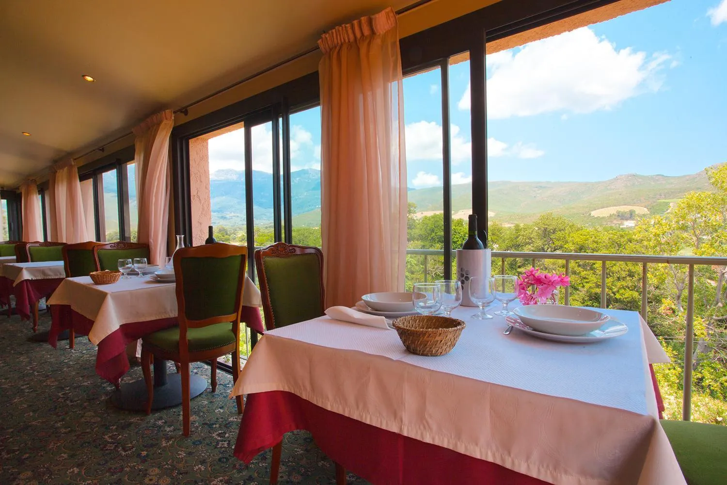 Une salle de restaurant lumineuse offre une vue sur un paysage montagneux.