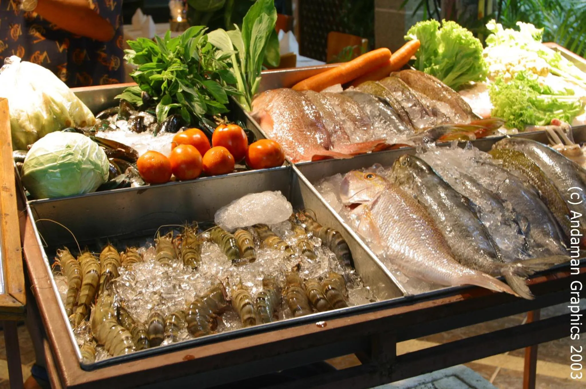 Présentation de poissons frais et de légumes sur un comptoir réfrigéré.