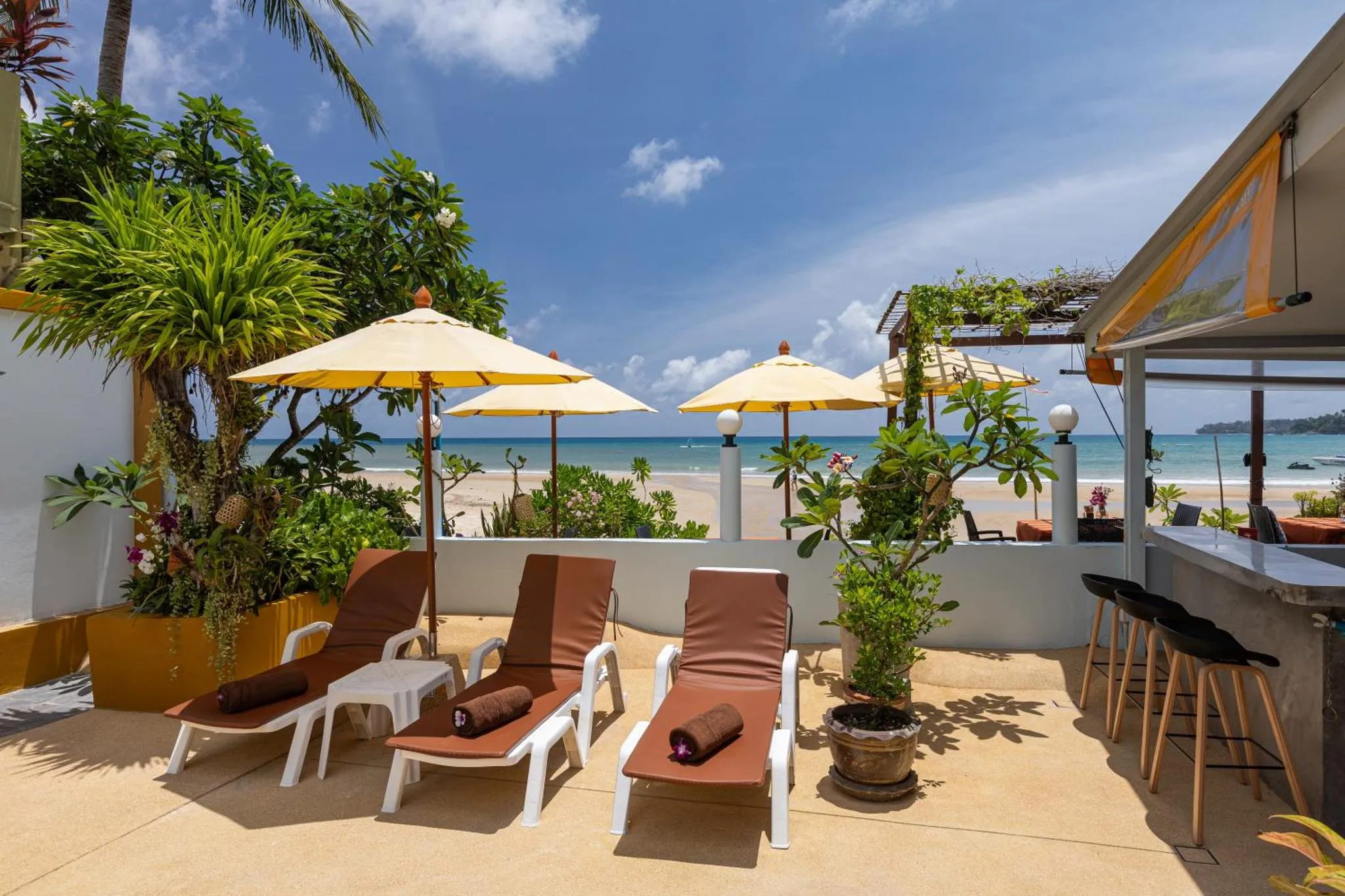 Transats et parasols sur une terrasse ensoleillée avec vue sur la mer.