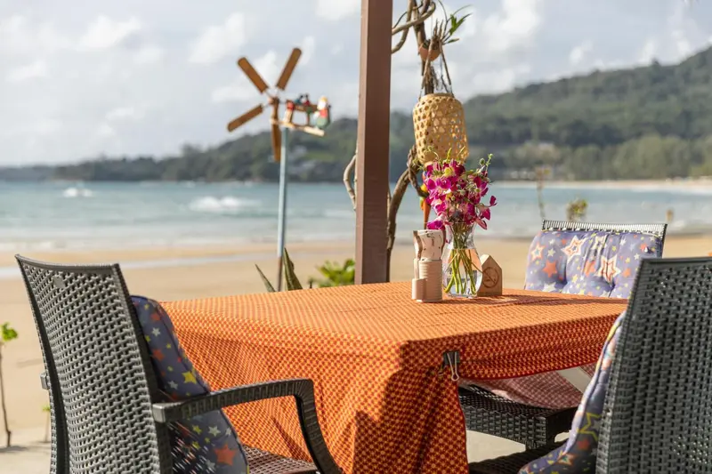 Table et chaises sur une terrasse en bord de mer avec une vue sur la plage.