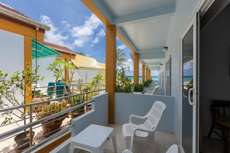 Terrasse ombragée avec mobilier en plastique blanc donnant sur la mer.