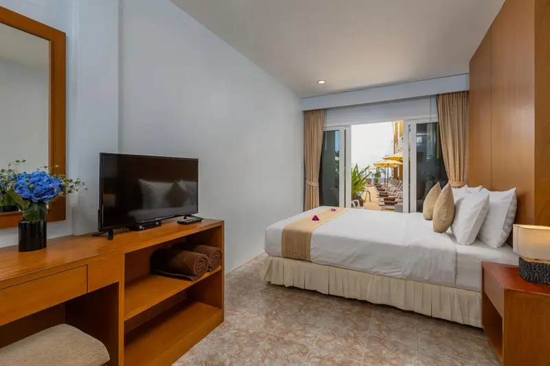 Une chambre lumineuse avec un grand lit et un téléviseur.