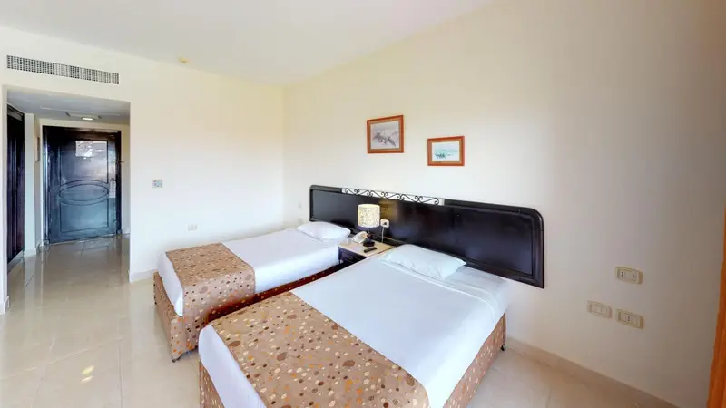 Chambre lumineuse avec deux lits simples et une décoration sobre.