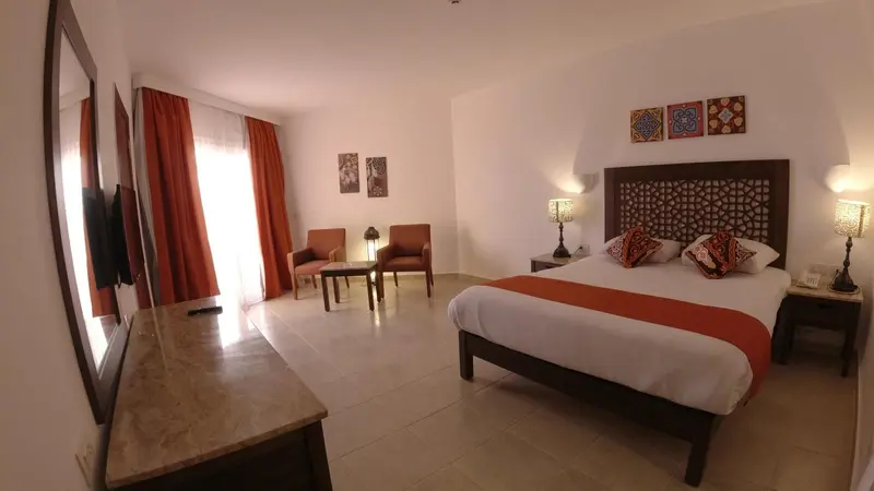 Une chambre lumineuse avec un grand lit et un coin salon.