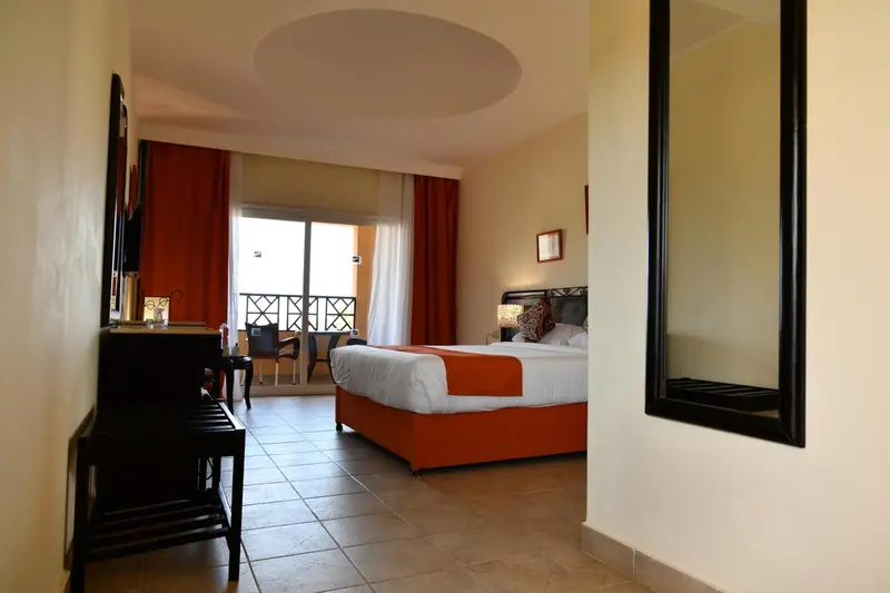Une chambre lumineuse avec un grand lit et un accès à un balcon.