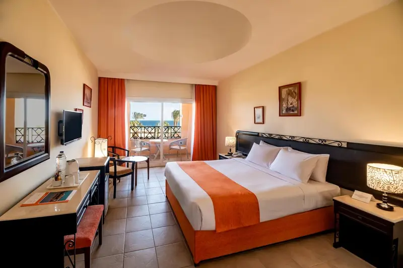 Chambre lumineuse avec un grand lit et un coin salon.