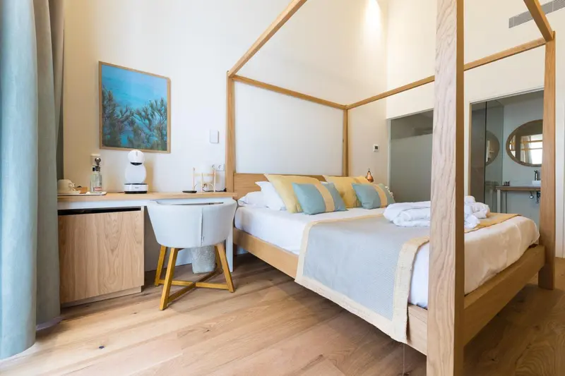 Une chambre lumineuse avec un grand lit et un bureau en bois.