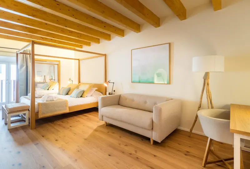 Une chambre lumineuse avec un lit à baldaquin et un canapé.