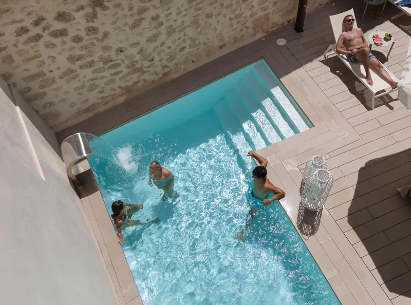 Vue aérienne d'une piscine rectangulaire avec des personnes s'amusant dans l'eau.