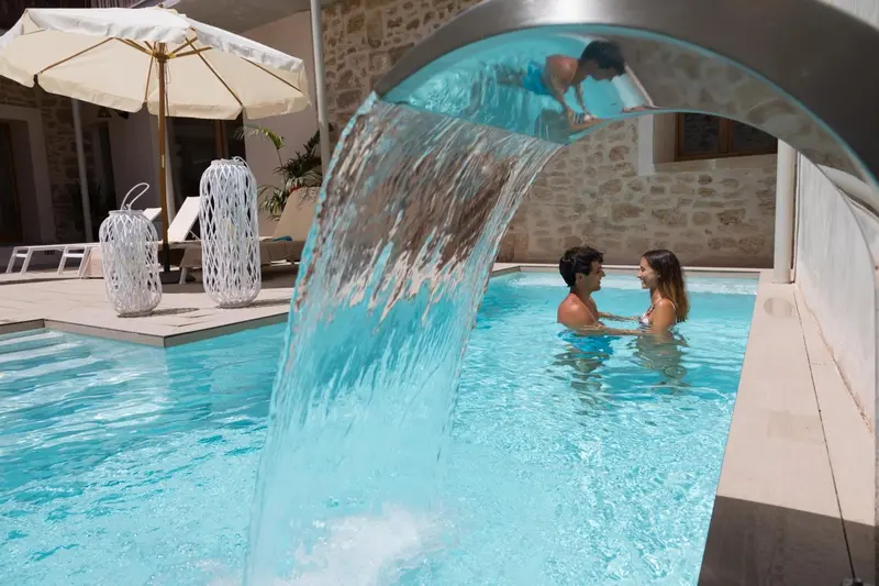 Un couple se détend dans une piscine avec une cascade artificielle.