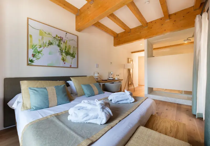 Une chambre lumineuse avec un grand lit recouvert de coussins et de couvertures.
