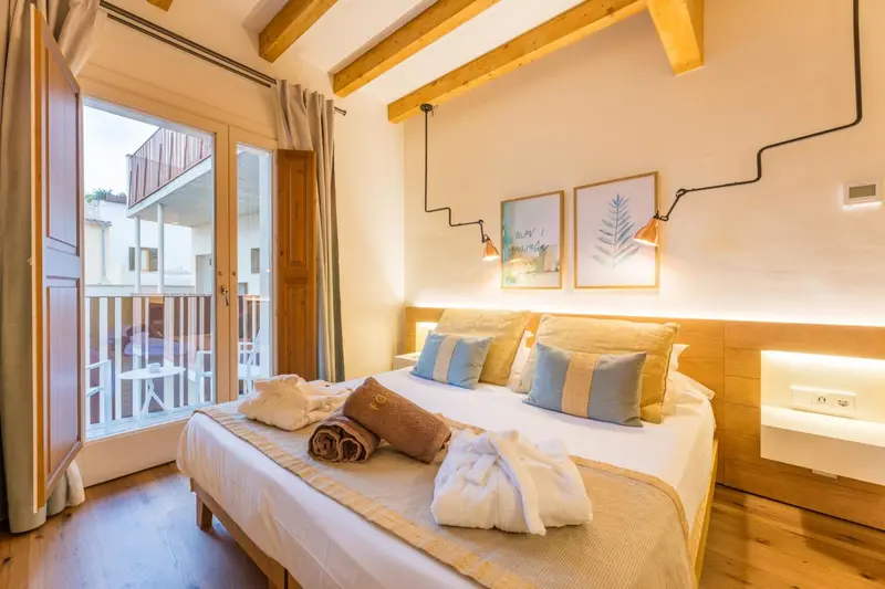 Une chambre lumineuse avec un grand lit et un balcon fleuri.