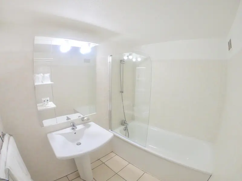 Une salle de bain lumineuse avec baignoire et lavabo.