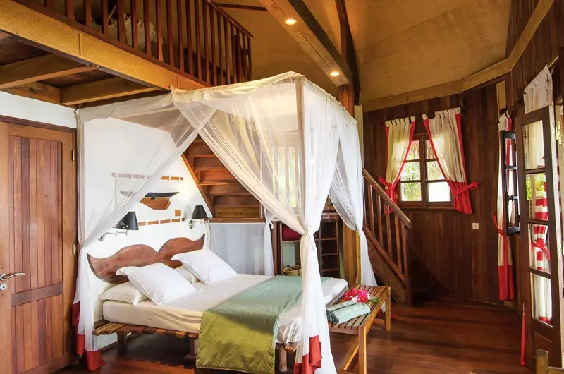 Une chambre avec un lit à baldaquin en bois et moustiquaire.