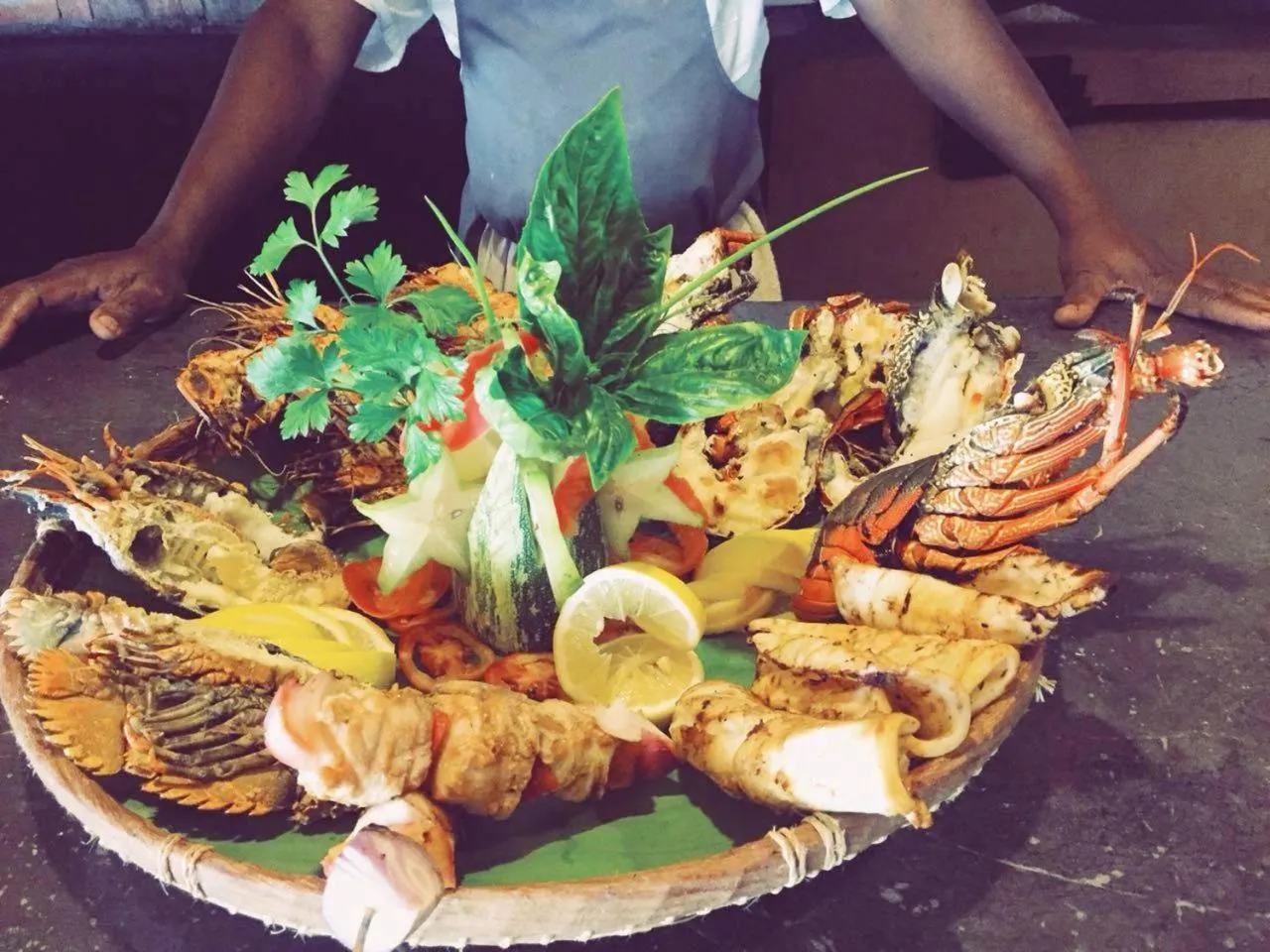 Assiette généreuse de fruits de mer grillés, décorée de légumes et de citron.