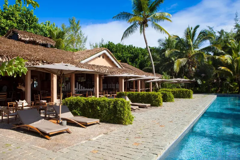 Transats et végétation luxuriante bordent une piscine turquoise.
