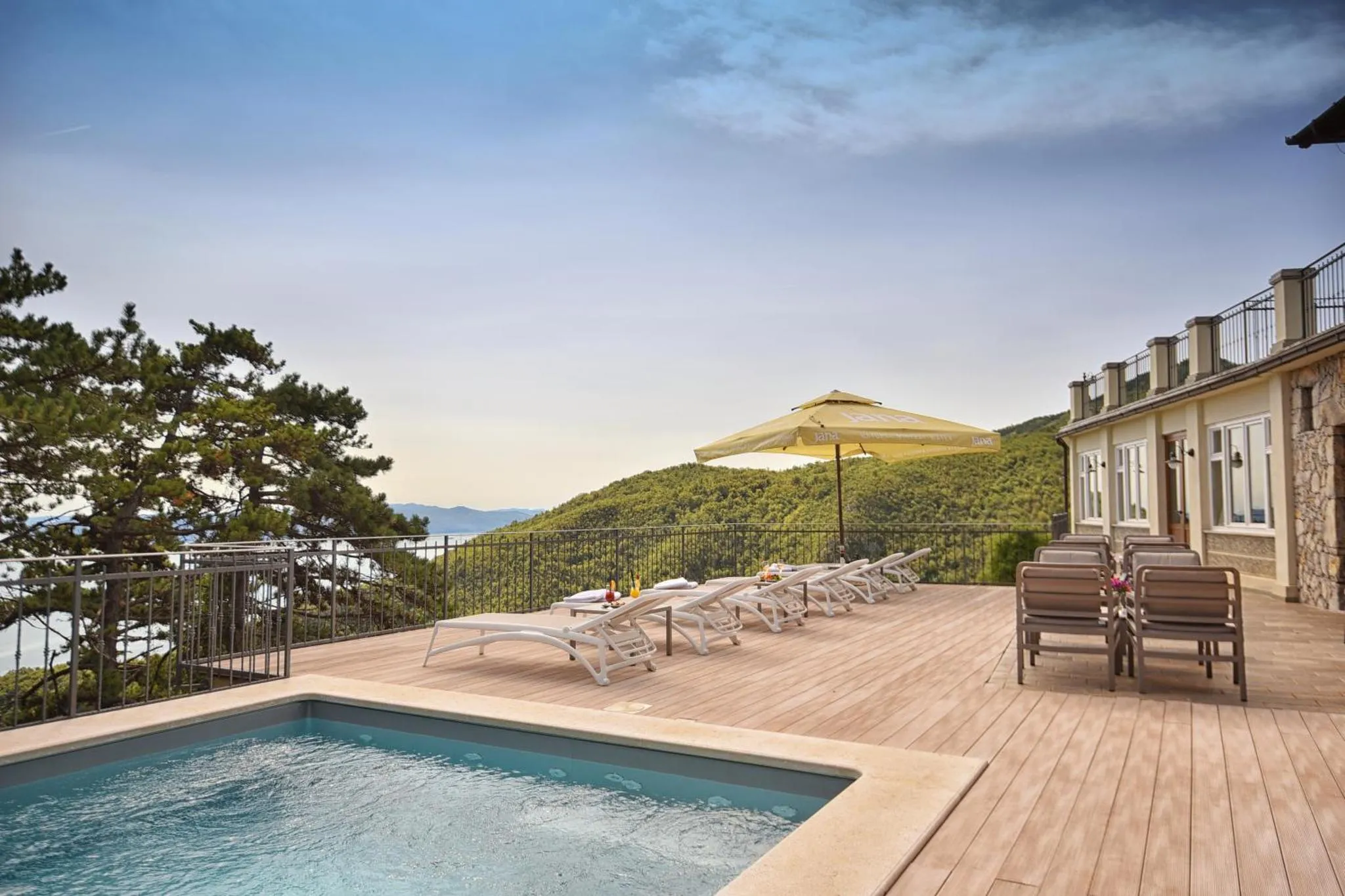 Terrasse avec transats et petite piscine offrant une vue sur la mer et les collines.