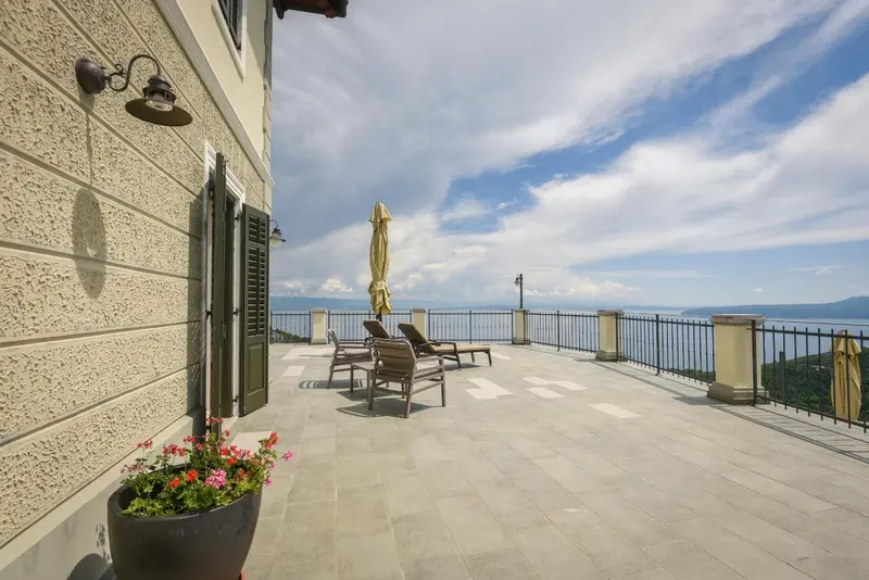 Terrasse ensoleillée avec mobilier de jardin et vue sur la mer.