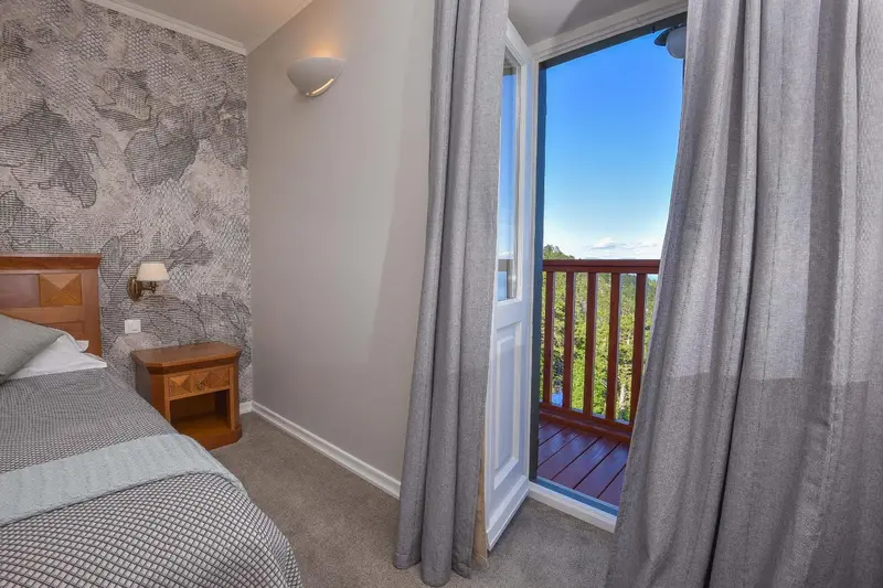 Une chambre lumineuse s'ouvre sur une terrasse avec vue sur la végétation.