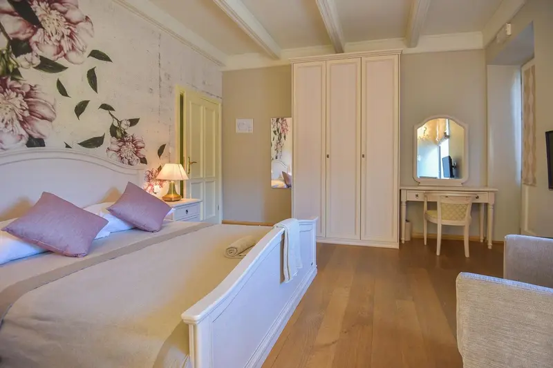 Une chambre lumineuse avec un grand lit à baldaquin et un mobilier blanc.
