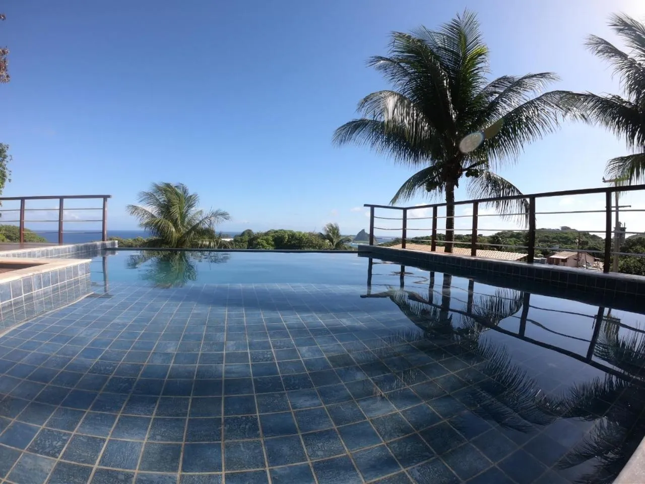 Piscine à débordement avec vue sur la mer et la végétation.