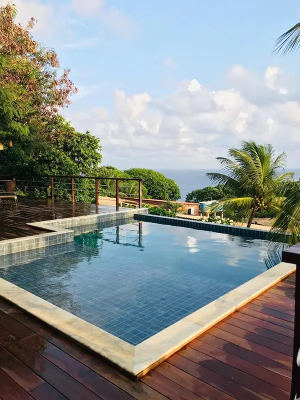 Une piscine à débordement surplombe un paysage côtier verdoyant.