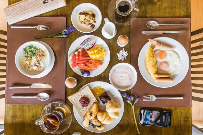 Une table est dressée pour un repas avec des assiettes de fruits, de céréales et d'œufs.