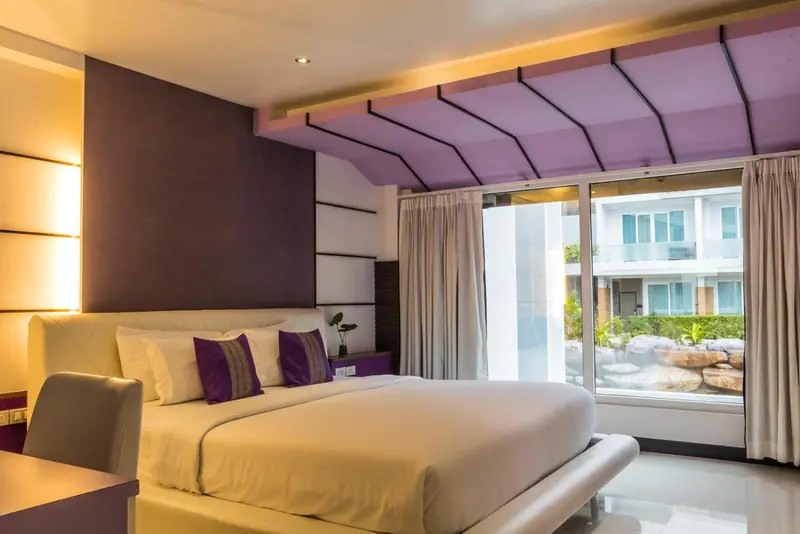 Une chambre lumineuse avec un grand lit et une vue sur un jardin.
